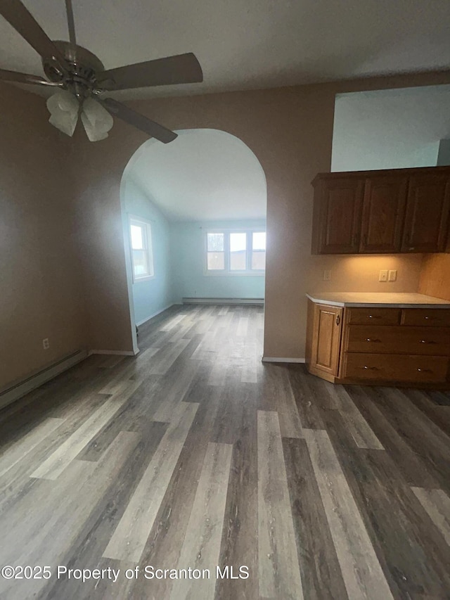 interior space featuring arched walkways, lofted ceiling, dark wood-type flooring, a ceiling fan, and baseboards