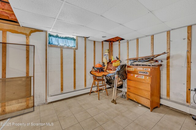 below grade area featuring baseboard heating and a paneled ceiling