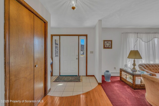 entryway with a baseboard heating unit, plenty of natural light, light wood-style floors, and baseboards