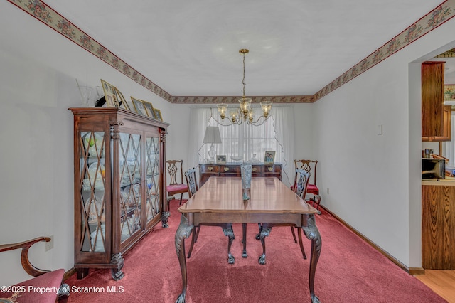 carpeted dining space featuring a notable chandelier and baseboards