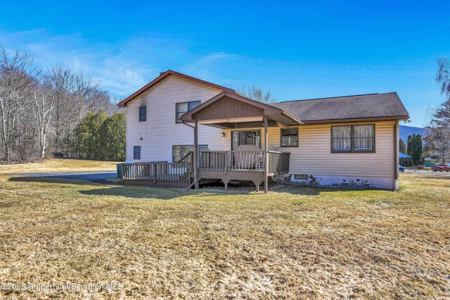 back of house with a wooden deck and a lawn