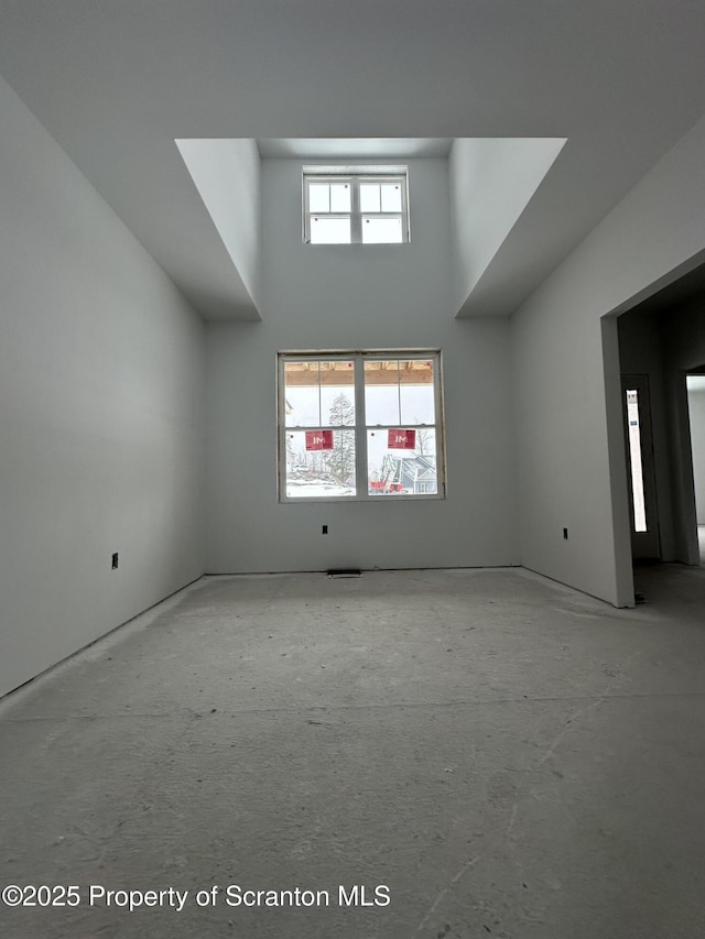 unfurnished room featuring a wealth of natural light and a towering ceiling