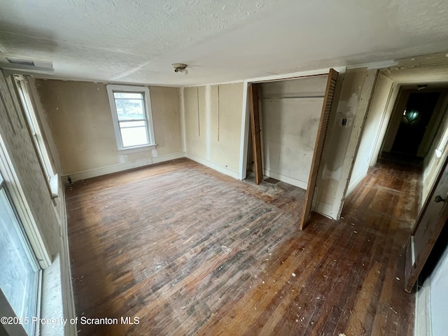 unfurnished bedroom featuring a closet, a textured ceiling, and wood-type flooring