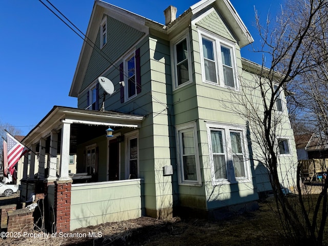 view of home's exterior featuring covered porch and a chimney