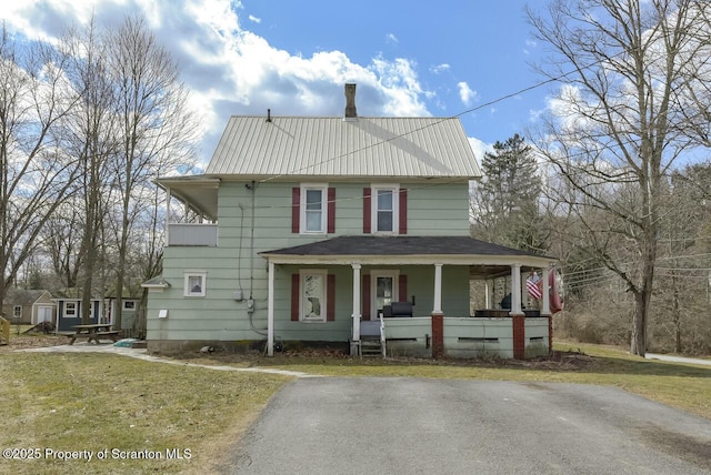 view of front of house featuring covered porch, metal roof, and a front yard