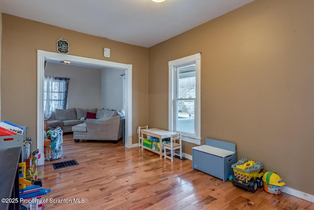 game room featuring baseboards, plenty of natural light, visible vents, and wood finished floors