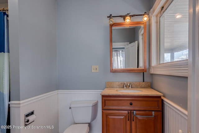 bathroom with vanity, toilet, and wainscoting