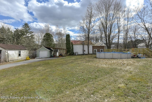 view of yard with an outbuilding, driveway, fence, a garage, and a fenced in pool