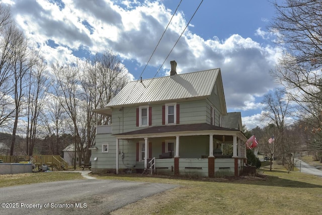 view of front of house with crawl space, metal roof, a porch, and a front lawn