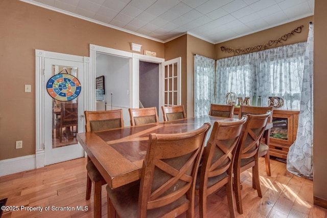 dining space featuring light wood-style flooring, crown molding, and baseboards