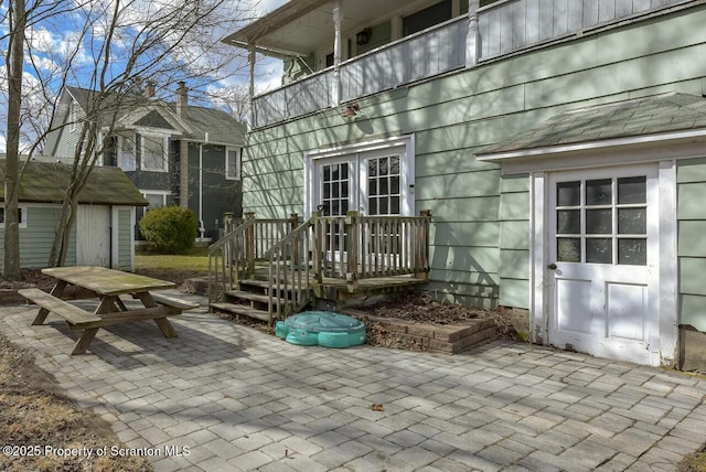 view of patio / terrace featuring a shed, french doors, a balcony, an outbuilding, and outdoor dining space