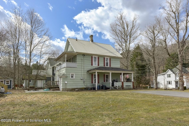 view of front of property featuring covered porch, metal roof, and a front lawn