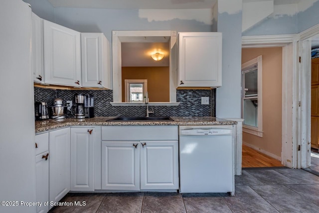 kitchen with backsplash, white cabinets, dishwasher, and a sink