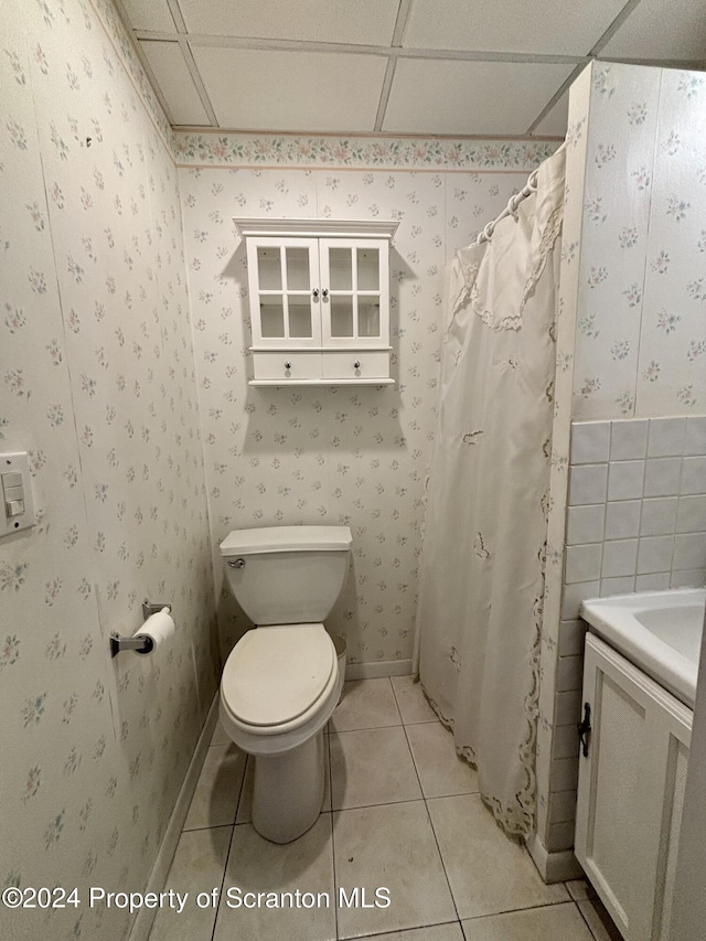 bathroom featuring tile patterned flooring, vanity, toilet, and a drop ceiling