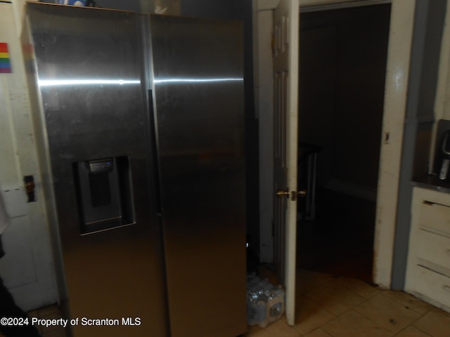 kitchen with white cabinets, stainless steel refrigerator with ice dispenser, and tile patterned floors