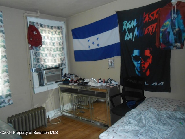 bedroom featuring radiator heating unit, cooling unit, and hardwood / wood-style floors