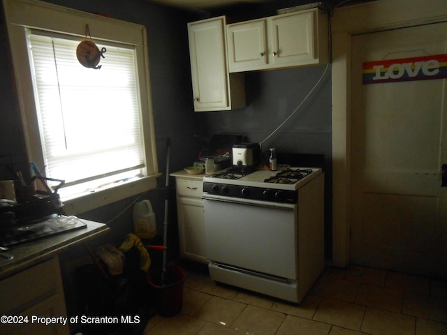 kitchen featuring light tile patterned floors, white gas stove, and cream cabinets