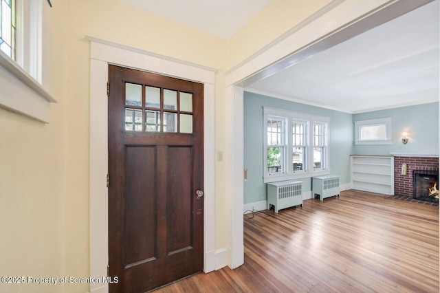 908 Prescott Ave, Scranton, PA 18510 - entrance foyer featuring radiator heating unit, wood finished floors, crown molding, and a brick fireplace
