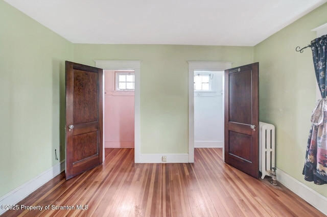 908 Prescott Ave, Scranton, PA 18510 - unfurnished bedroom with radiator heating unit, wood-type flooring, and a spacious closet
