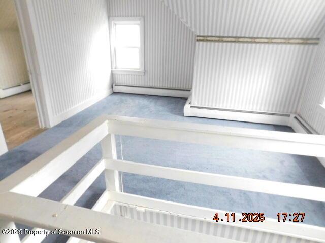 stairway featuring a baseboard heating unit