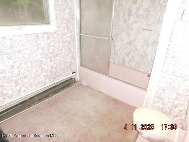 bathroom featuring shower / bath combination with glass door and toilet