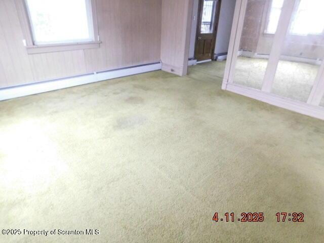 carpeted empty room featuring a baseboard radiator and a wealth of natural light
