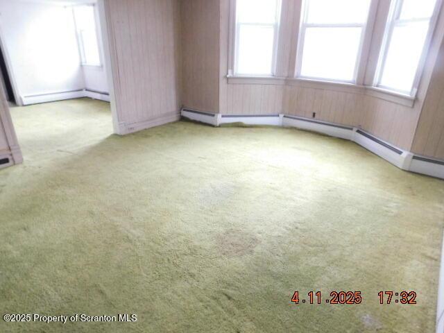 carpeted spare room featuring a baseboard radiator