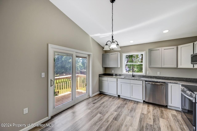 kitchen featuring pendant lighting, light wood finished floors, stainless steel appliances, a sink, and vaulted ceiling