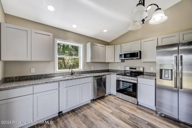 kitchen with stainless steel appliances, light wood-type flooring, white cabinetry, pendant lighting, and a sink