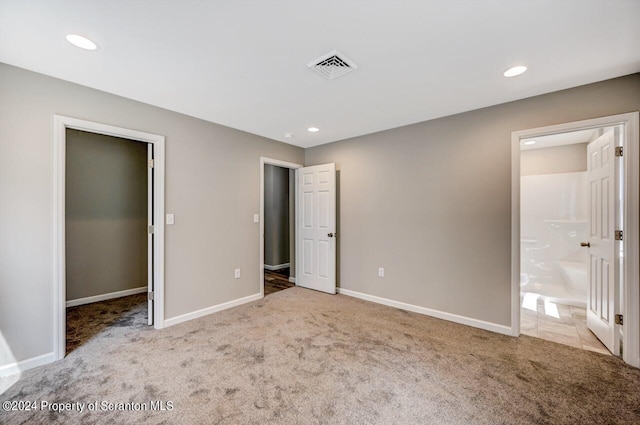 unfurnished bedroom featuring light carpet, visible vents, baseboards, and a spacious closet