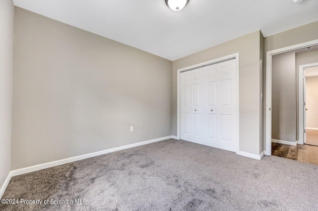 unfurnished bedroom with a closet, carpet, and baseboards