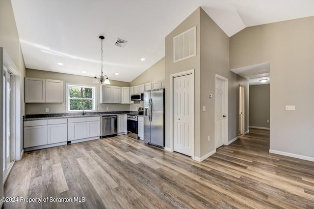 kitchen with stainless steel appliances, visible vents, hanging light fixtures, and light wood-style flooring