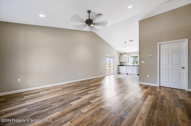 unfurnished living room with ceiling fan, dark wood-style flooring, visible vents, baseboards, and vaulted ceiling