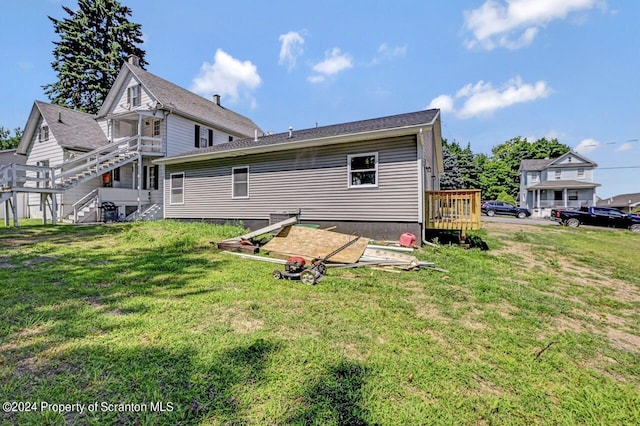 back of property with a deck, a yard, and stairway