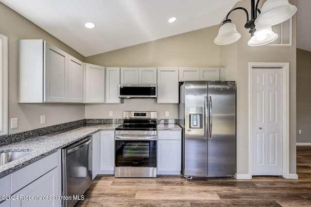 kitchen featuring light stone countertops, vaulted ceiling, appliances with stainless steel finishes, and white cabinets