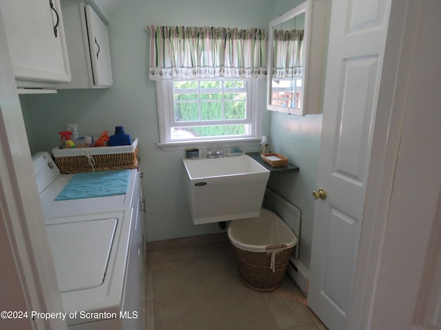 washroom with cabinets, separate washer and dryer, light tile patterned flooring, and sink