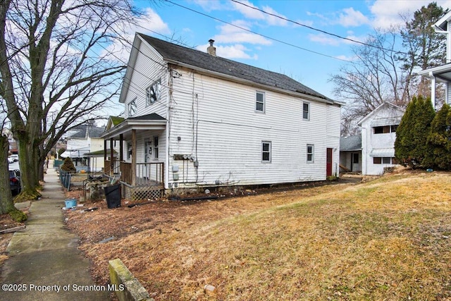 view of side of home with a lawn and a chimney