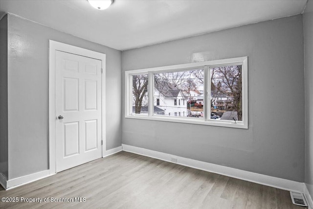 spare room with visible vents, baseboards, and wood finished floors
