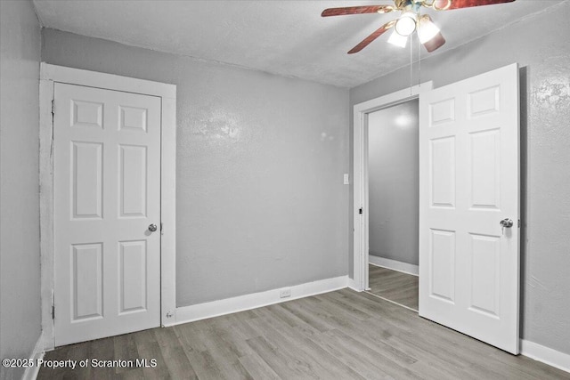 unfurnished bedroom with ceiling fan, baseboards, and wood finished floors