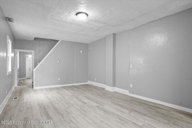 interior space with visible vents, a textured ceiling, baseboards, and wood finished floors