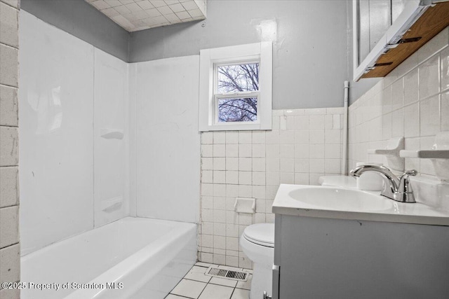 full bathroom featuring toilet, vanity, visible vents, tile walls, and tile patterned floors