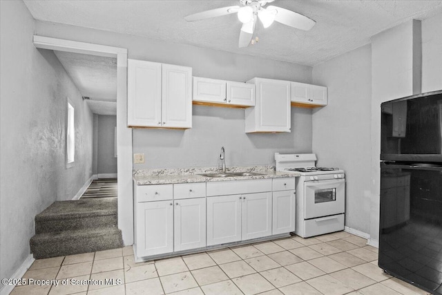 kitchen with a textured ceiling, a sink, white cabinetry, freestanding refrigerator, and gas range gas stove