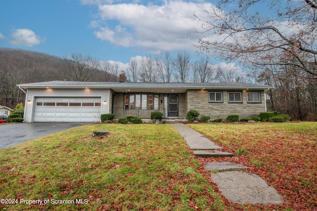 ranch-style home with covered porch, a garage, and a front lawn