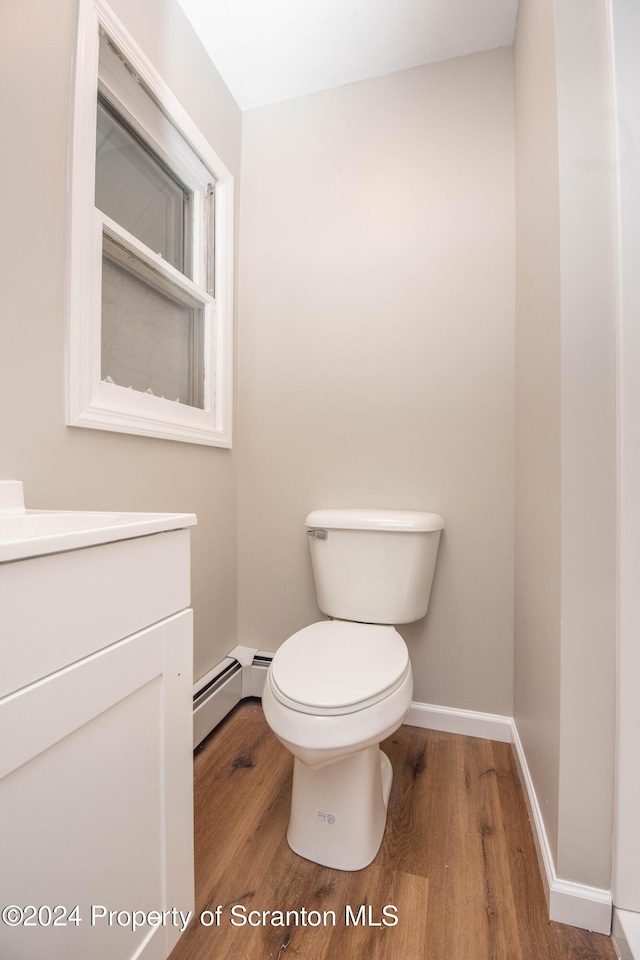 bathroom with wood-type flooring, vanity, toilet, and baseboard heating