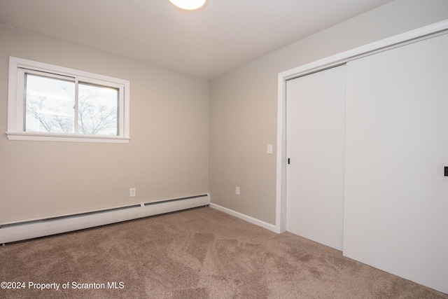 unfurnished bedroom with a closet, carpet floors, and a baseboard radiator