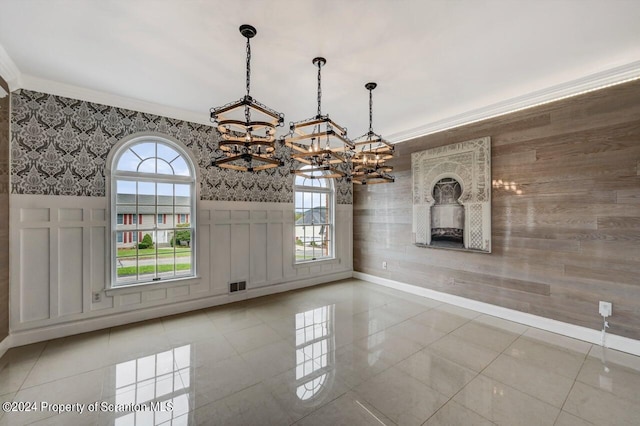 unfurnished dining area with tile patterned floors, crown molding, and an inviting chandelier