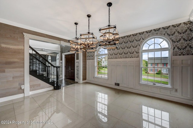 unfurnished dining area featuring a healthy amount of sunlight, ornamental molding, and an inviting chandelier