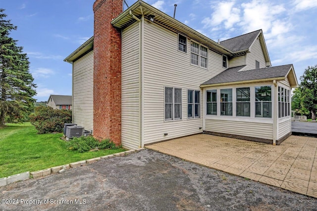 rear view of house with central AC, a lawn, a patio area, and a sunroom