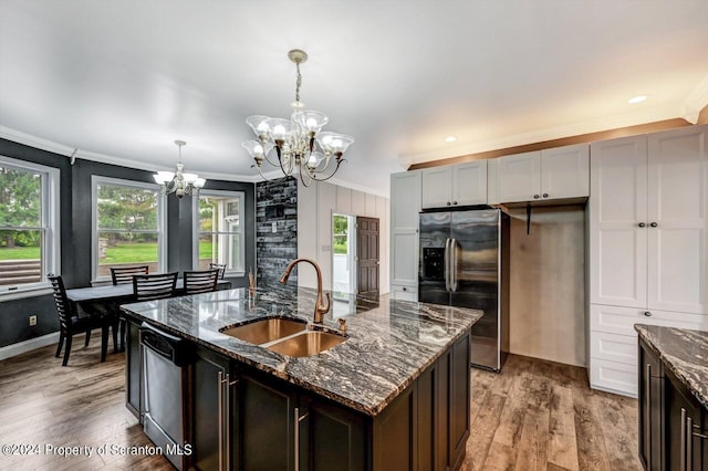 kitchen with dark stone counters, crown molding, sink, appliances with stainless steel finishes, and a notable chandelier