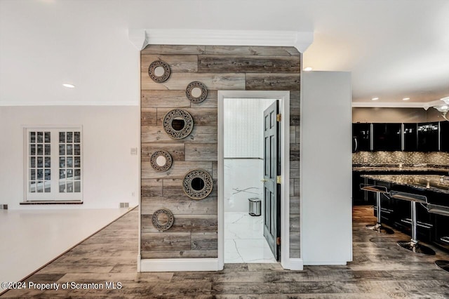 interior details featuring hardwood / wood-style flooring, ceiling fan, backsplash, and wooden walls